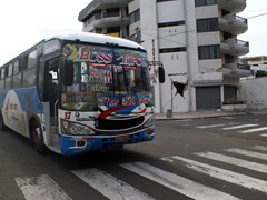 In Manta Equador setzt man auf bunte Busse.
Im Hintergrund ein vom Erdbeben beschdigtes Haus